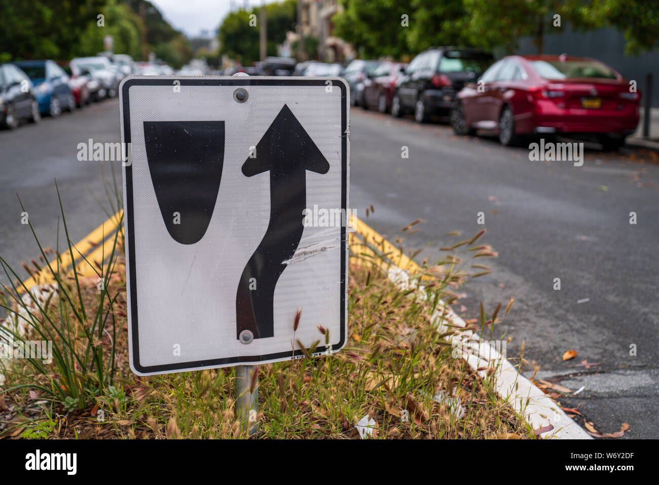 Traffic sign directing cars to go to right of median along crowded street Stock Photo