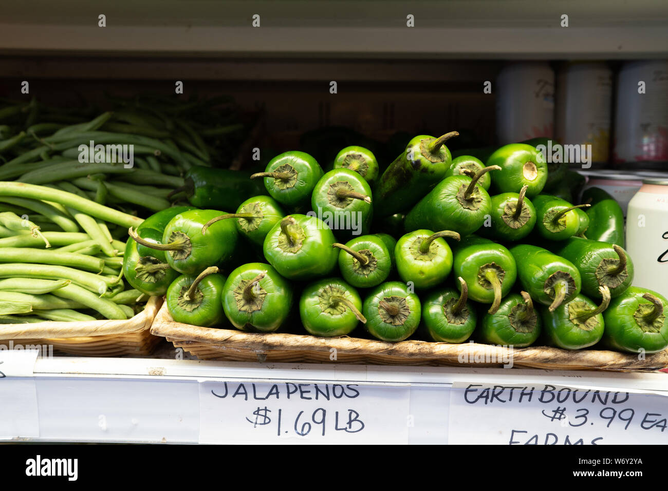 Jalapenos sitting in basket on shelf in grocery store produce section