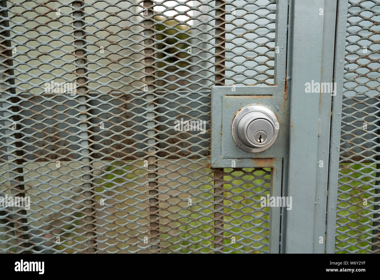 Keyhole for lock on outdoor green gate leading to building Stock Photo