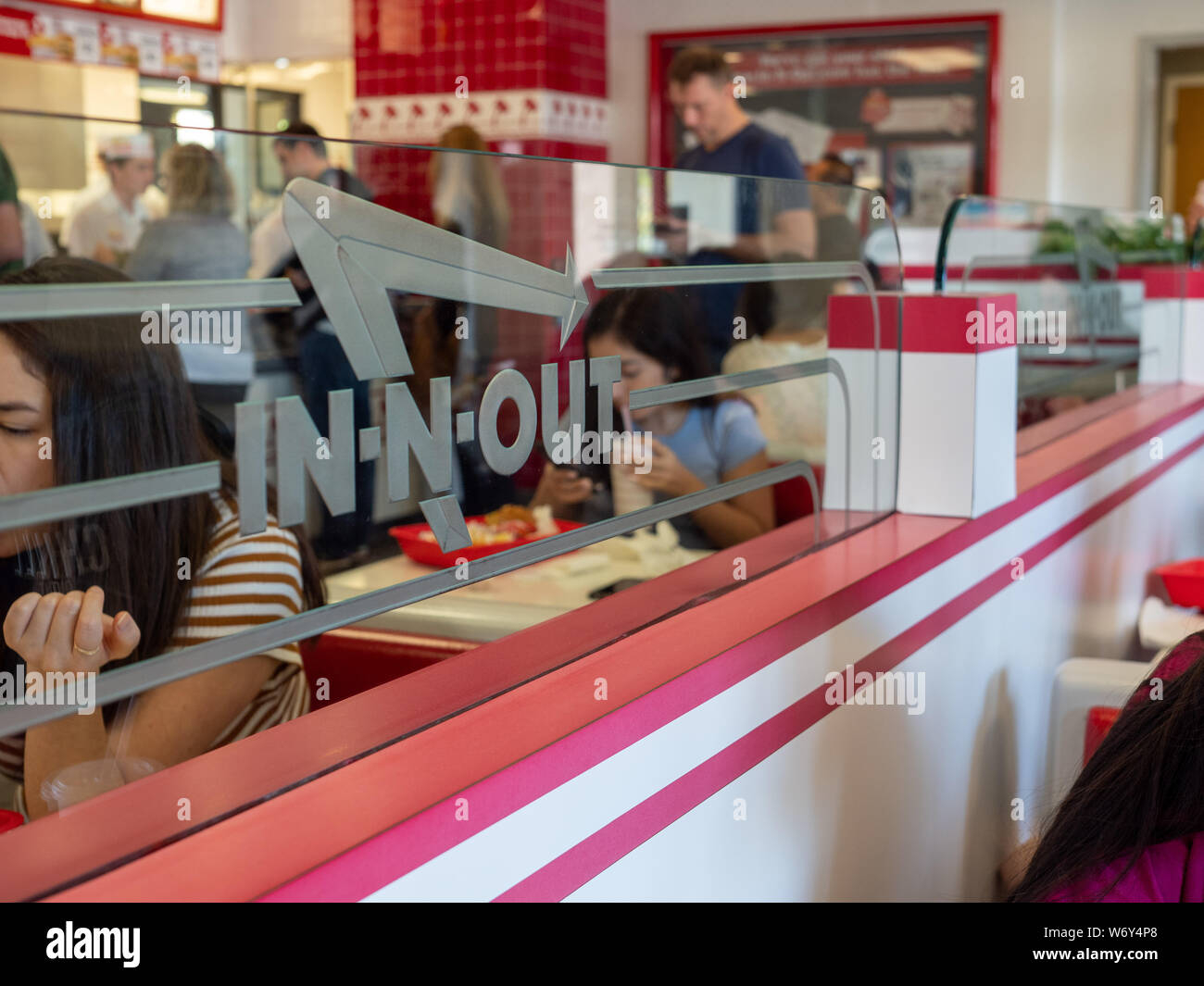 Diners eating at In-N-Out Burger location behind logo on glass divider Stock Photo