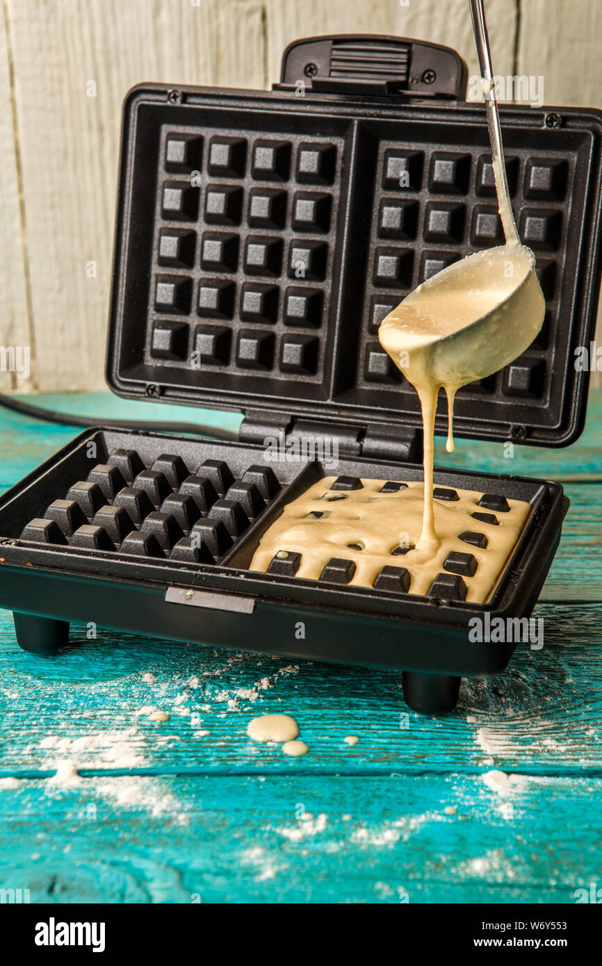 Making wafers at home. Pouring the dough into the waffle iron. Cooking background Stock Photo