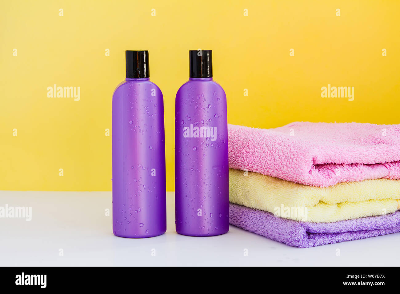 two purple cosmetic bottles and three bath towels for Spa treatments and body and hair care Stock Photo