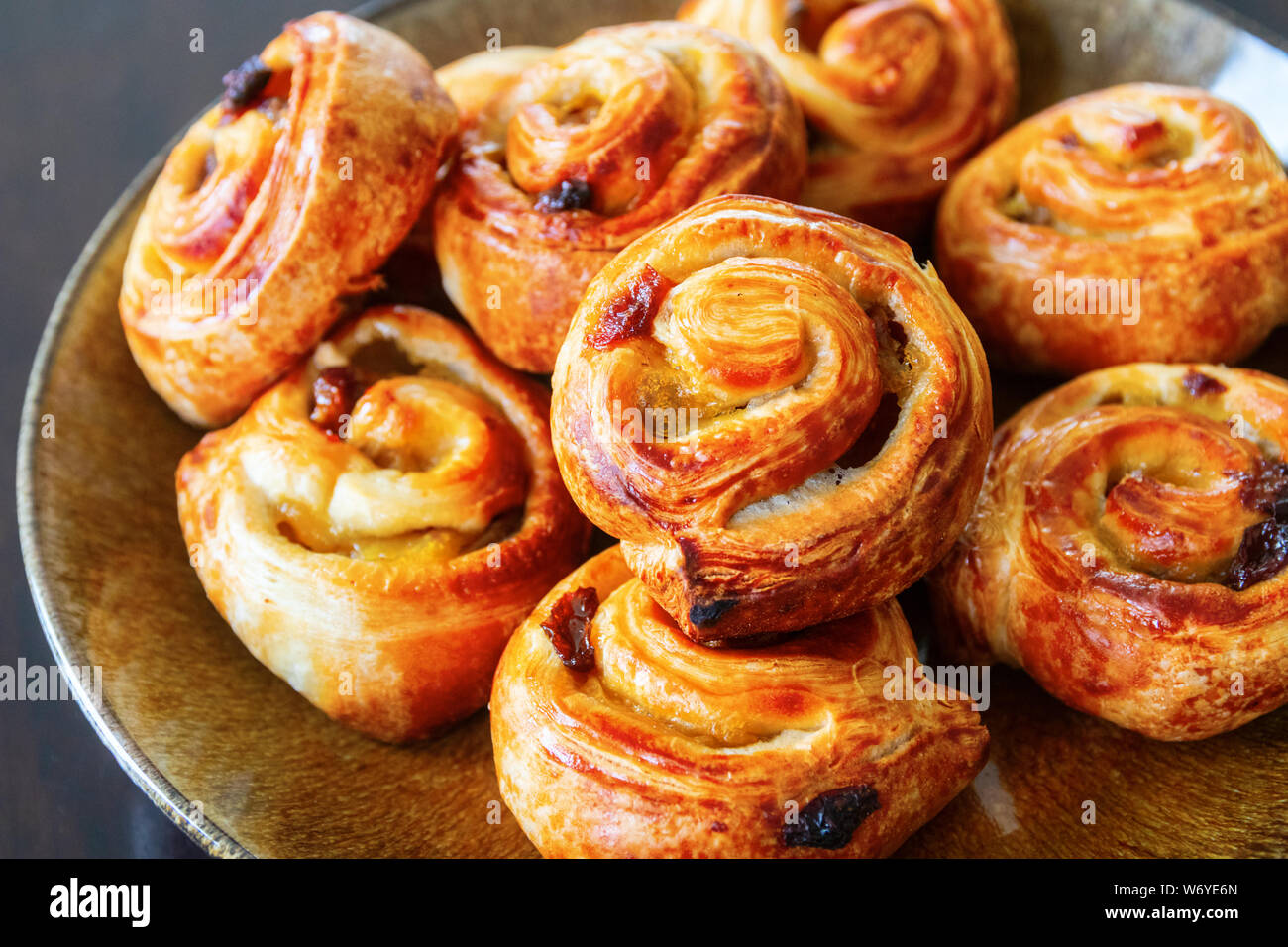 Delicicous golden brown pain aux raisins or raisin swirls, typical danish and french pastry, on a plate. Stock Photo