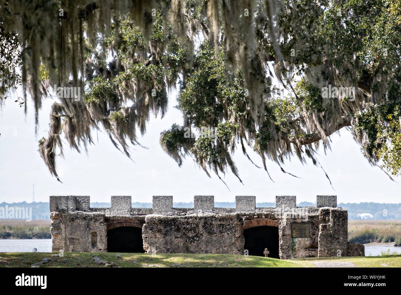 Spanish moss covers live oak trees hanging over the stone walls of the original arms magazine at the Fort Frederica National Monument, the original colonial settlement in St. Simons Island, Georgia. Fort Frederica was established by Georgia founder James Oglethorpe in 1736 to serve as a bulwark against the Spanish settlements in Florida, Stock Photo