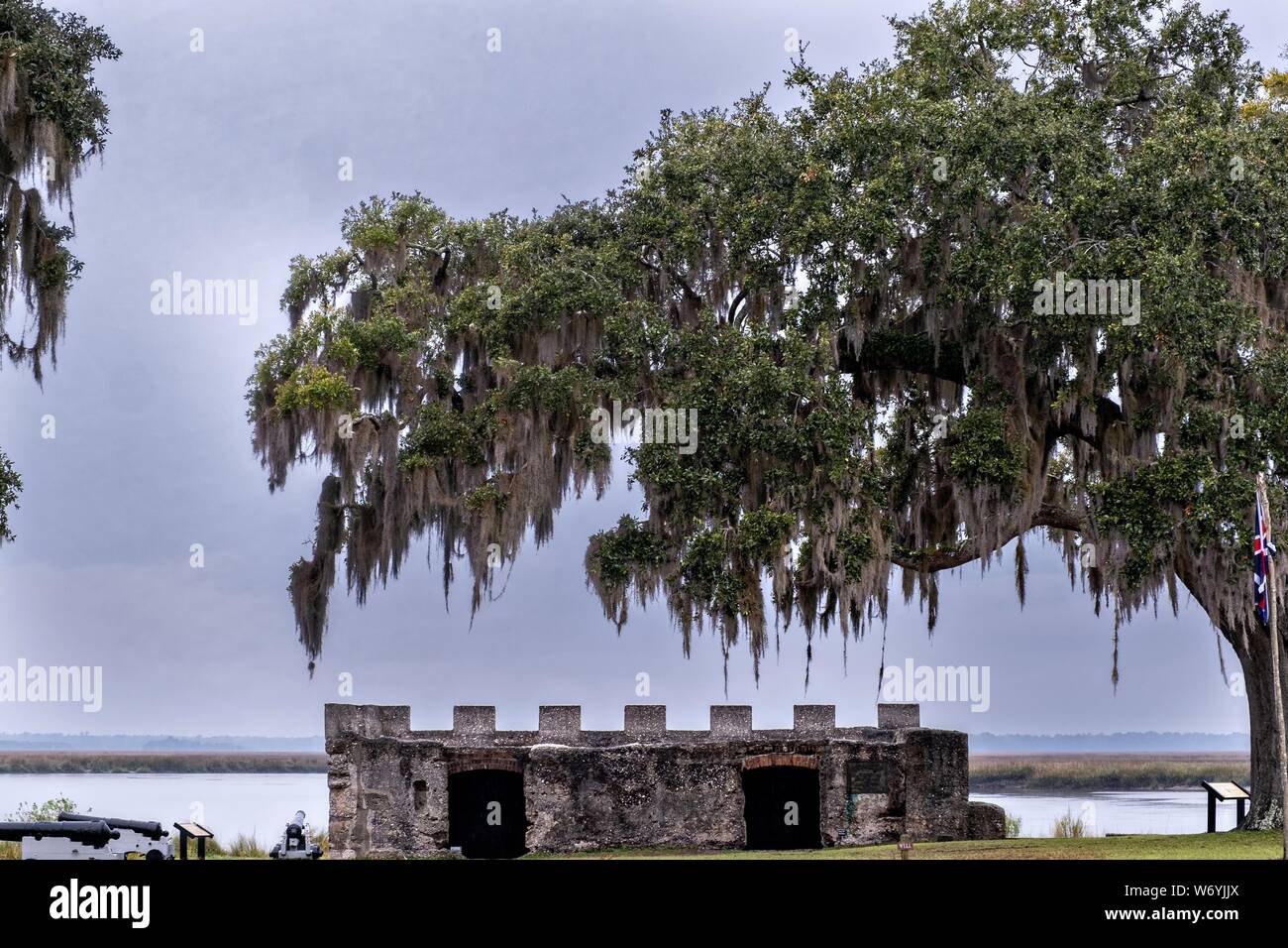 Spanish moss covers live oak trees hanging over the stone walls of the original arms magazine at the Fort Frederica National Monument, the original colonial settlement in St. Simons Island, Georgia. Fort Frederica was established by Georgia founder James Oglethorpe in 1736 to serve as a bulwark against the Spanish settlements in Florida, Stock Photo