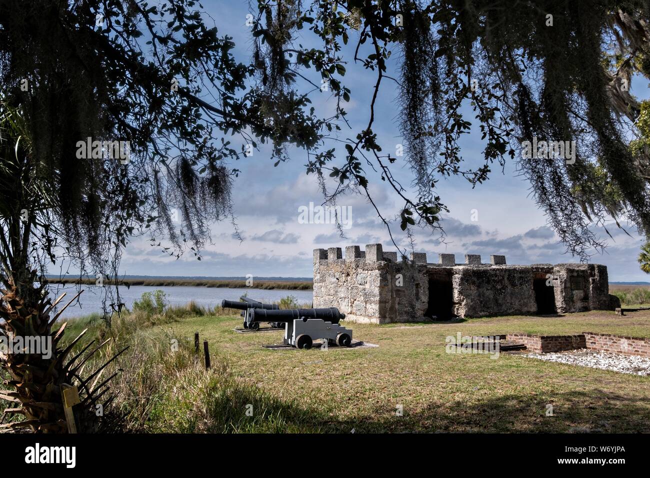 Spanish moss covers live oak trees hanging over the stone walls of the original arms magazine at the Fort Frederica National Monument, the original colonial settlement in St. Simons Island, Georgia. Fort Frederica was established by Georgia founder James Oglethorpe in 1736 to serve as a bulwark against the Spanish settlements in Florida, Stock Photo