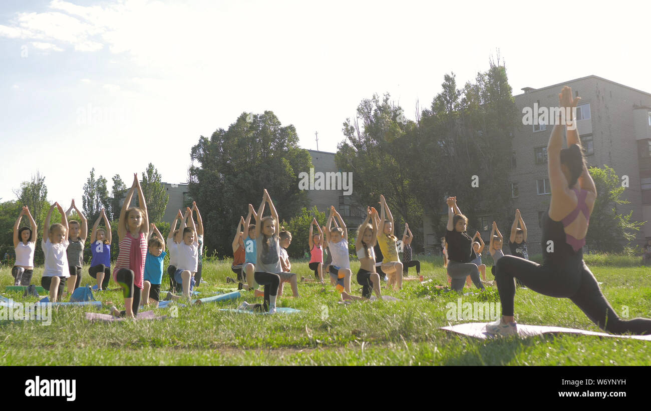 A large group of children engaged in yoga in the Park sitting on the ...