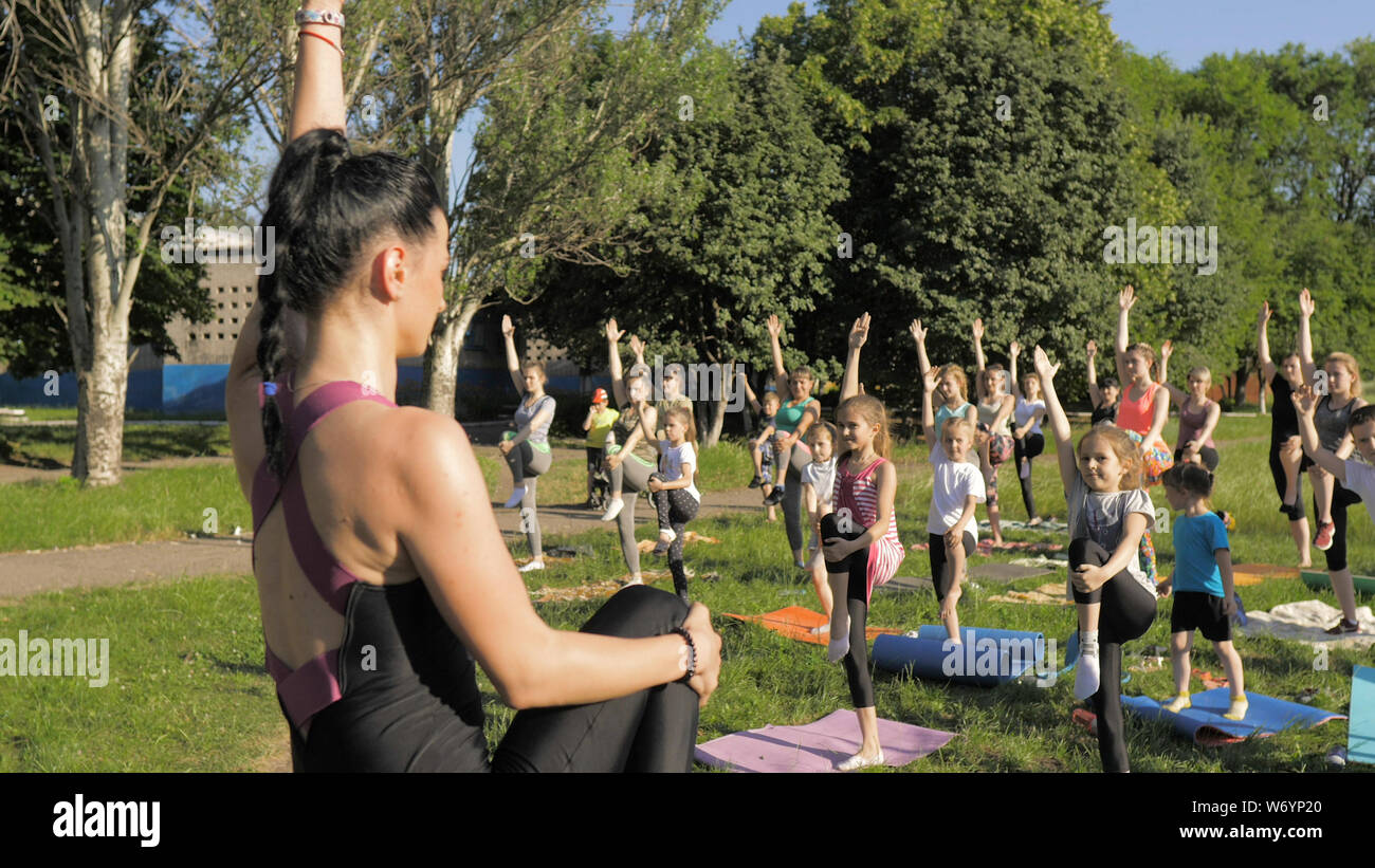 A large group of children engaged in yoga in the Park sitting on the ...