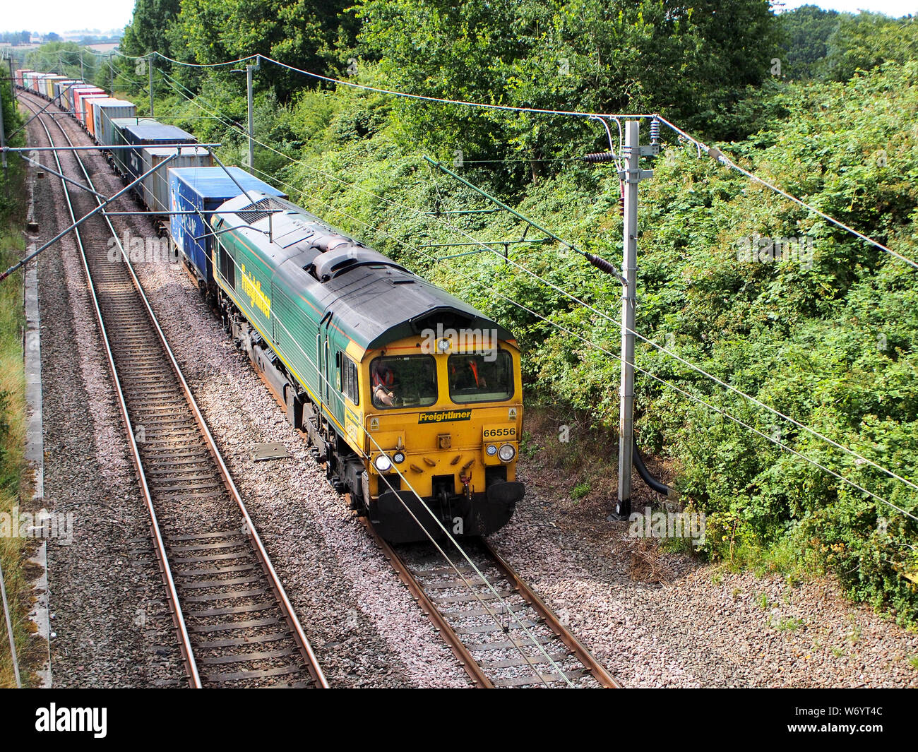 Freightliner Class 66556  hauls an intermodal freight train on the West Coast Mainline in Northamptonshire, UK Stock Photo