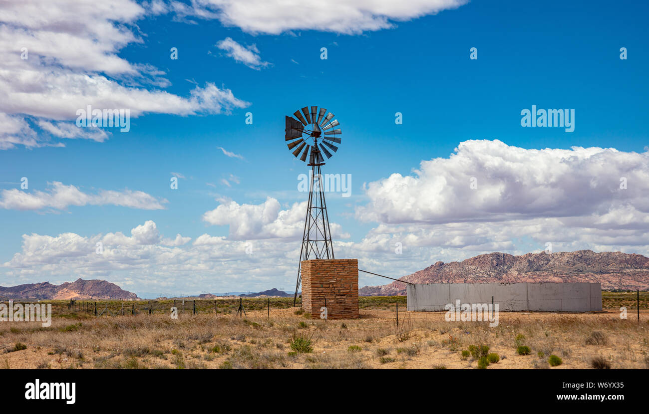 Windmill in an american countryside desert landscape, sunny spring day, blue sky with clouds. Stock Photo