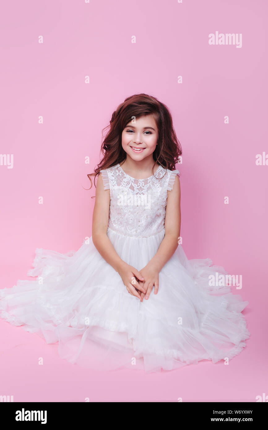 cute smiling little girl in princess dress sitting on pink background ...