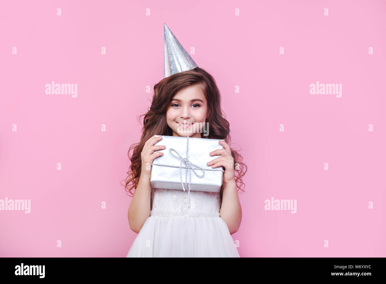 Portrait of cute little girl with gift box on pink background. Birthday ...