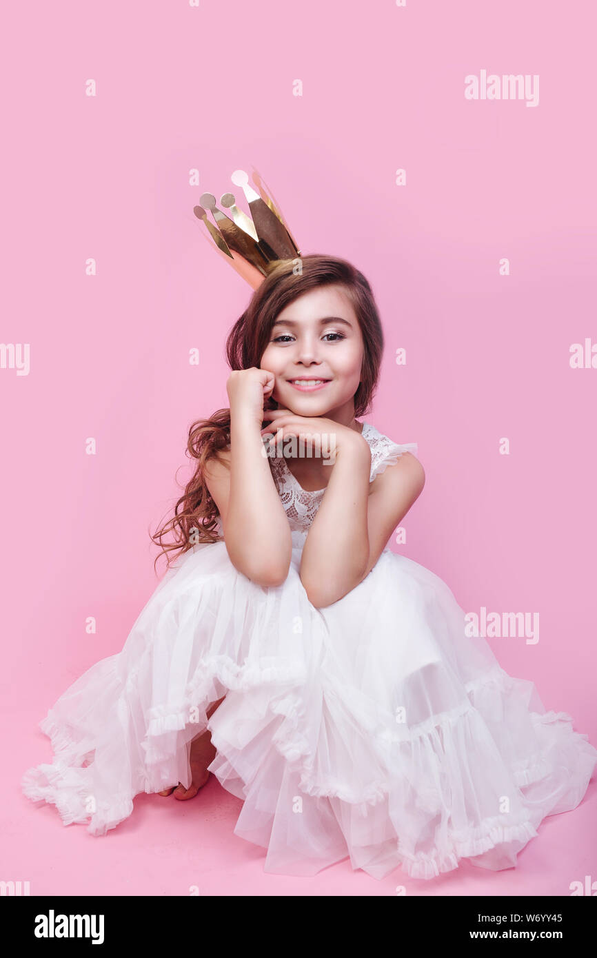 Little cute princess girl in gold crown and beautiful dress on pink ...