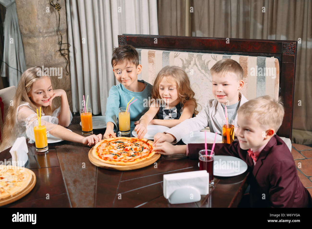 company of children eat pizza in the restaurant Stock Photo