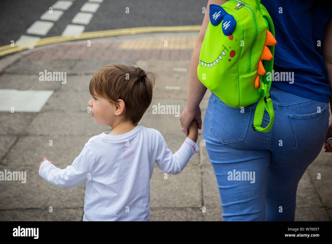 A child holding his mothers hand walking down a street Stock Photo