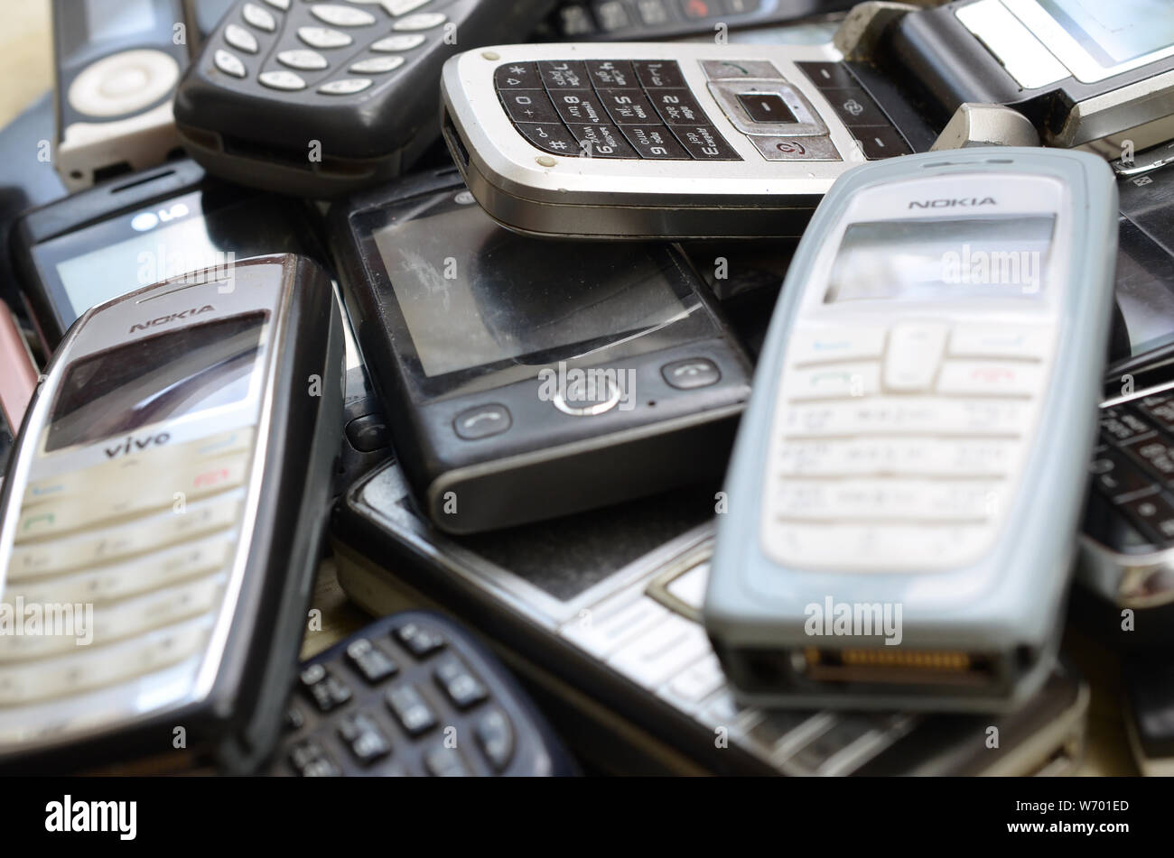 KHARKIV, UKRAINE - JULY 30, 2019: Bunch of old used outdated mobile phones. Recycling electronics of many brands was sold in the market cheap. Close u Stock Photo