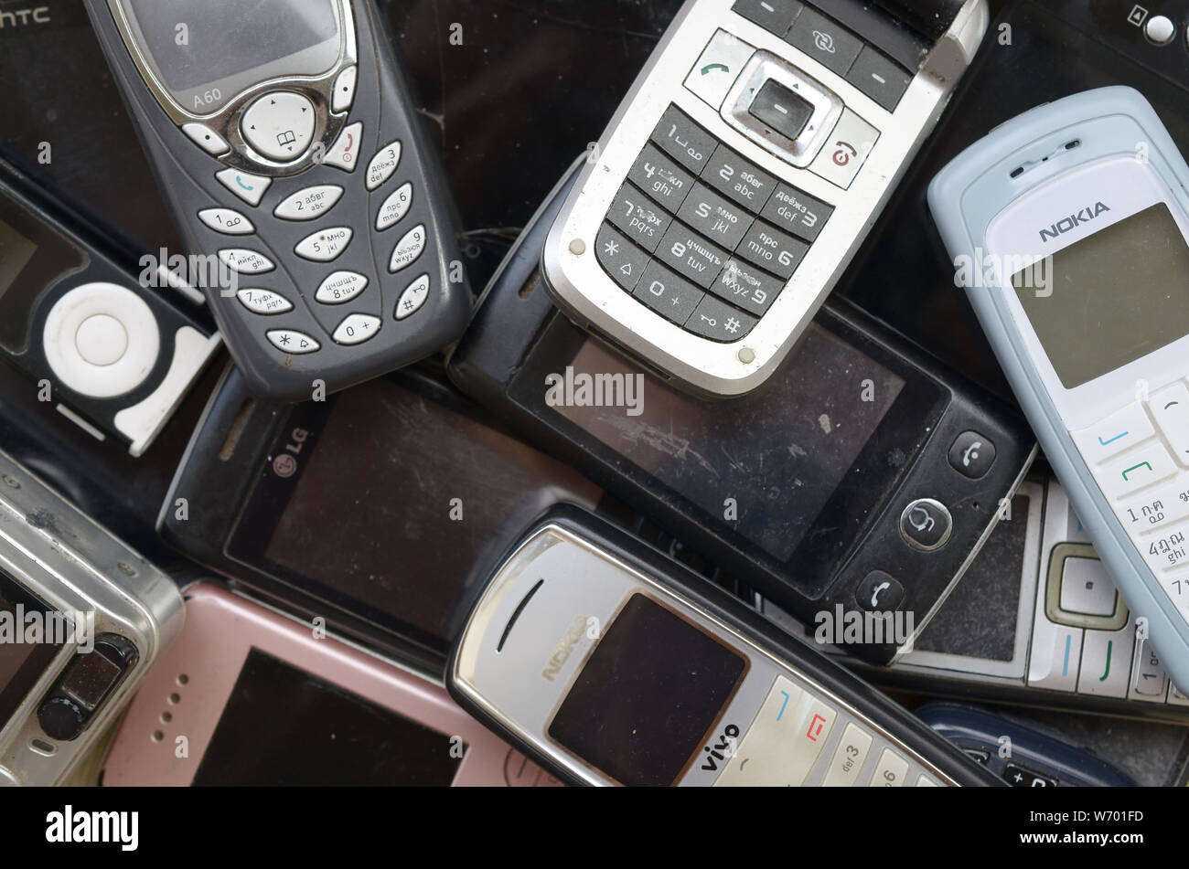 KHARKIV, UKRAINE - JULY 30, 2019: A few old used outdated mobile phones. Recycling electronics of many brands was sold in the market cheap. Flat lay t Stock Photo