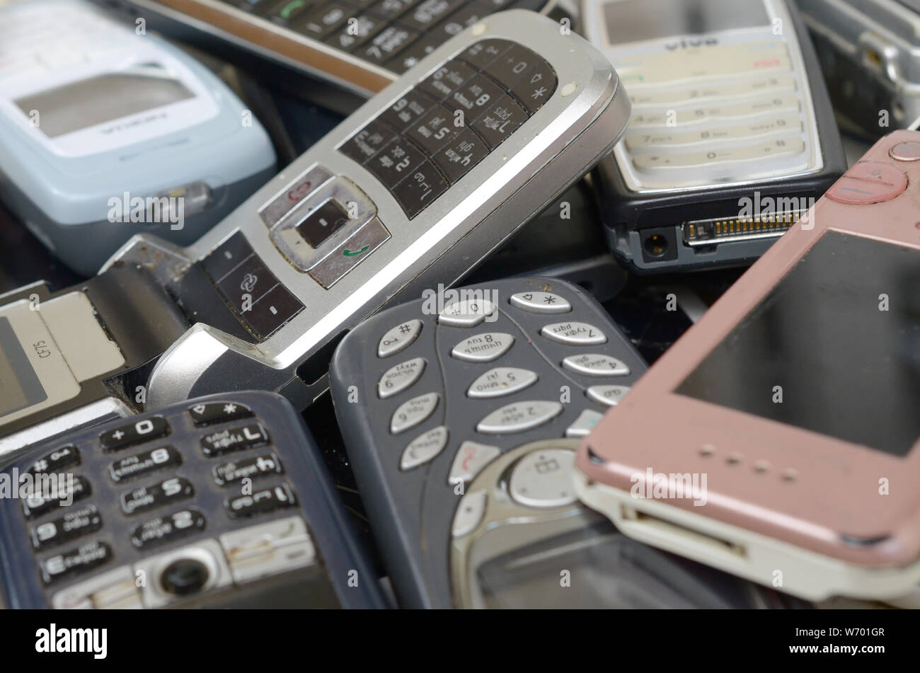 KHARKIV, UKRAINE - JULY 30, 2019: Bunch of old used outdated mobile phones. Recycling electronics of many brands was sold in the market cheap. Close u Stock Photo