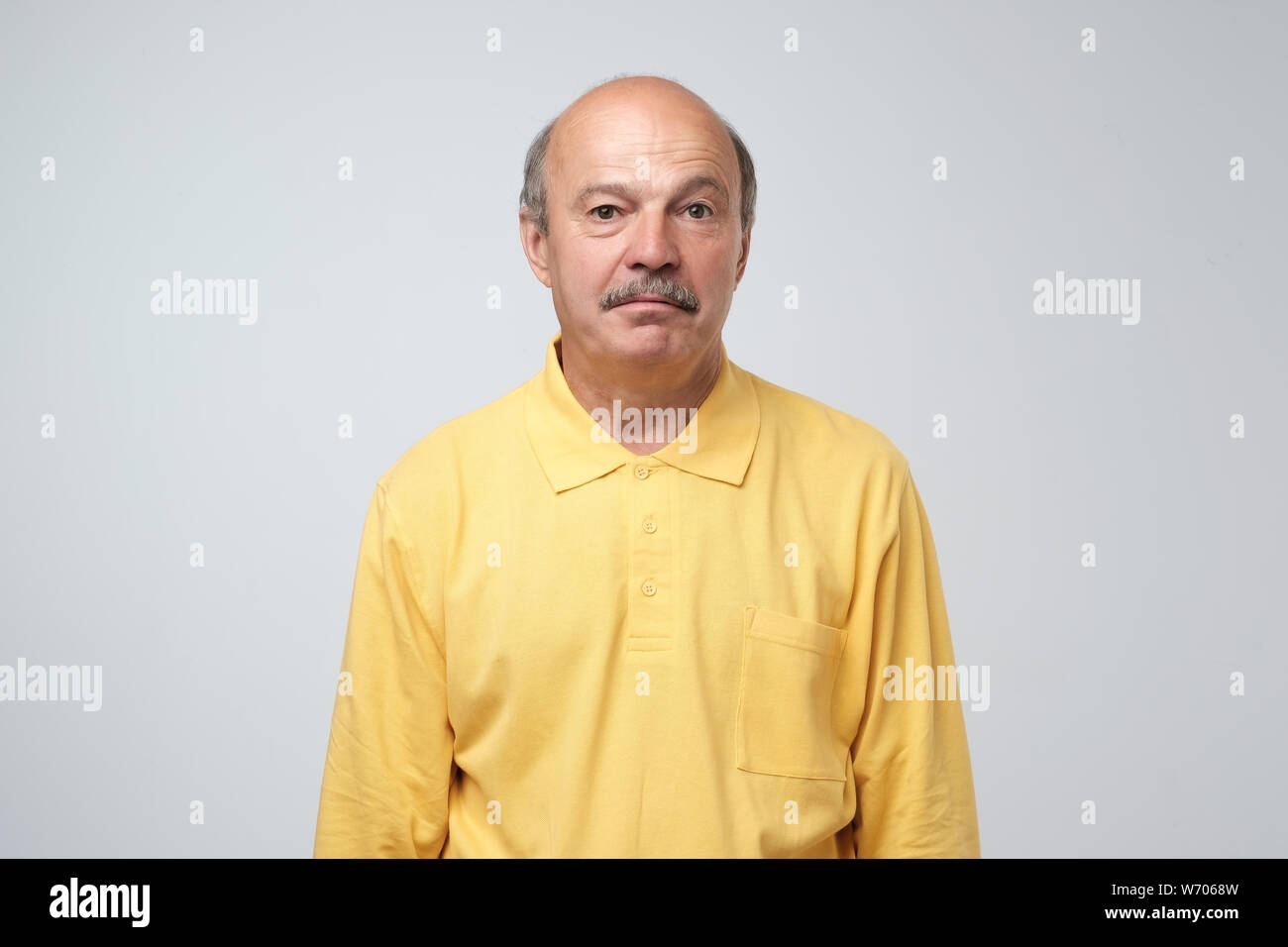 Sad upset mature hispanic guy in yellow pullover looking with guilt and sadness. Studio shot Stock Photo