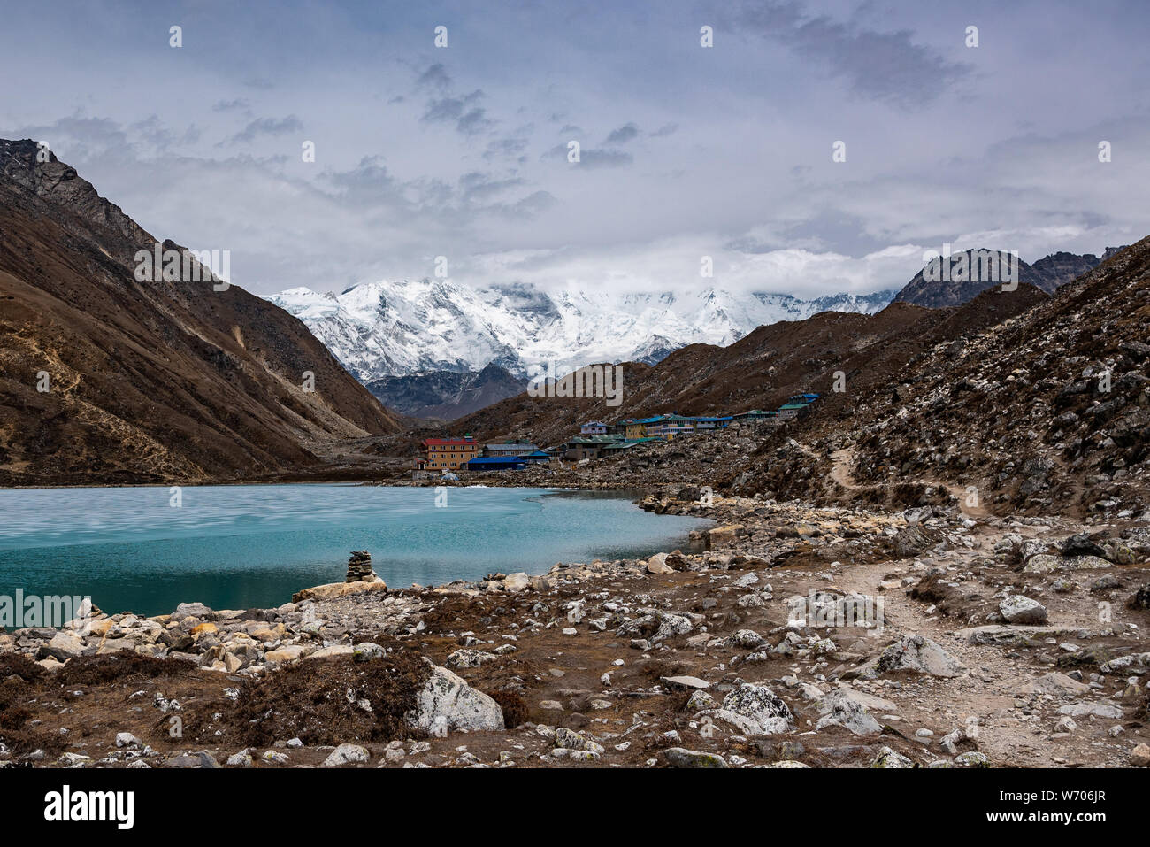 Gokyo lake with stone pyramid laid on its shore, and narrow trail leading to Gokyo town Stock Photo