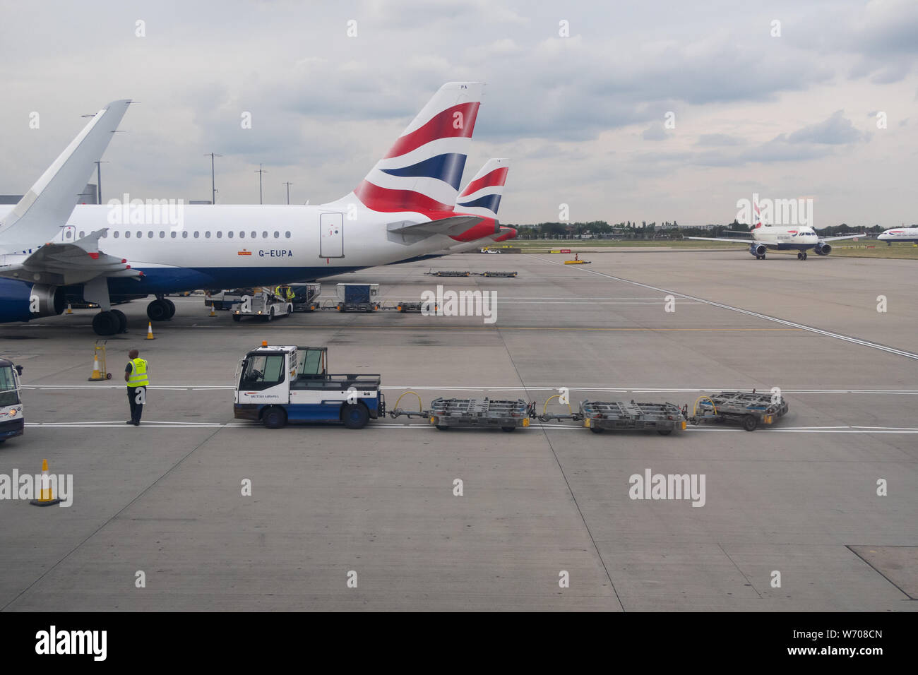 Baggage handers unload luggage cargo containers from a British Airways