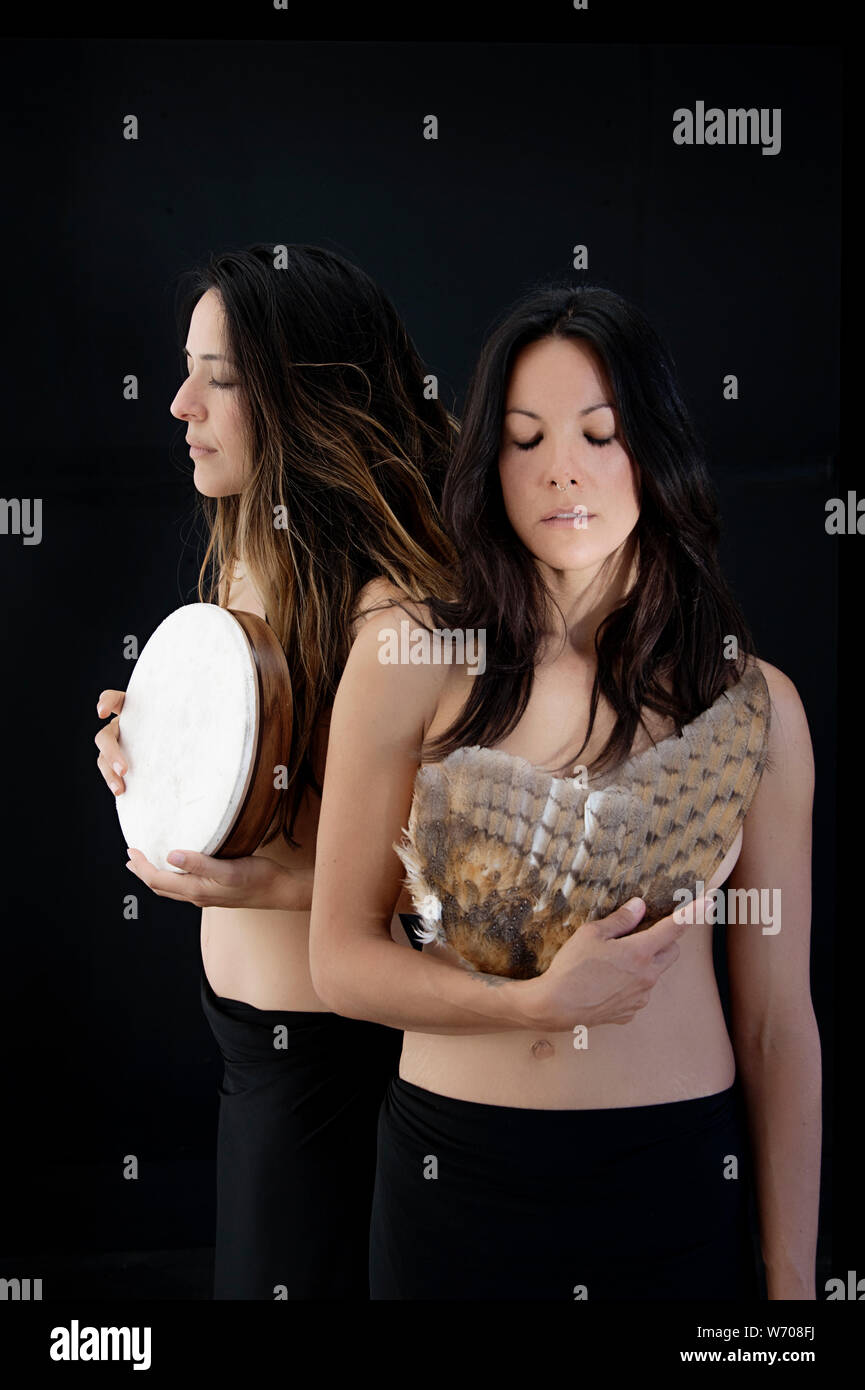 Two embodied shamanic women holidng an owl's wing and a drum. Stock Photo