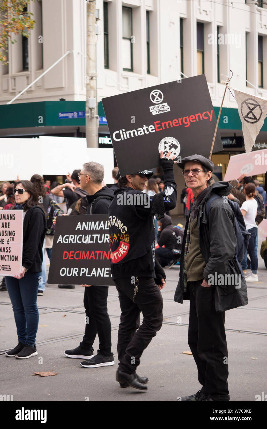 Middle aged protesters holding black "animal agriculture is decimating our planet" sign in Melbourne, Australia climate protest march. Stock Photo
