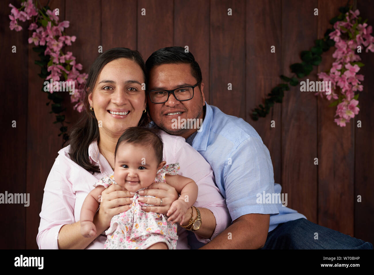 Happy family with small baby girl on wooden studio background Stock Photo -  Alamy