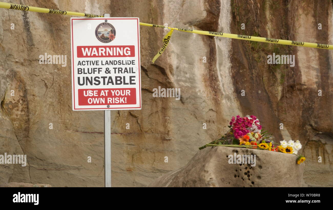 Signs and caution tape warn of unstable cliffs at Grandview Beach in Encinitas - site of a deadly bluff collapse. Flowers mourn the killed beachgoers. Stock Photo