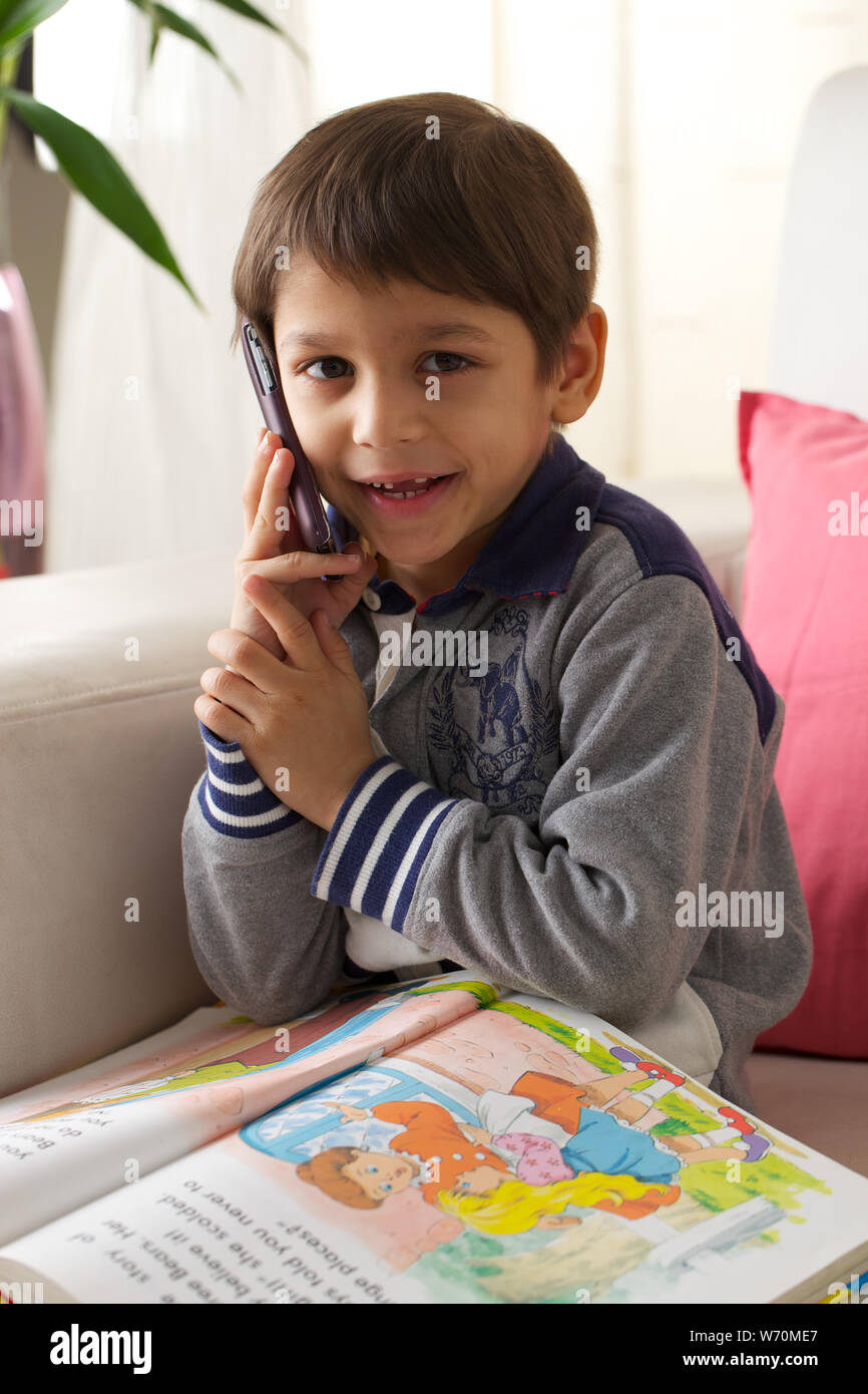 Boy talking on mobile phone and reading a book Stock Photo Alamy