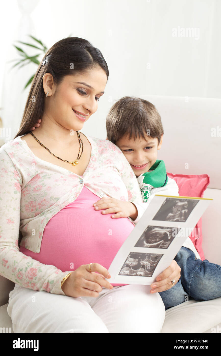 Pregnant mother examining ultrasound report with her son Stock Photo