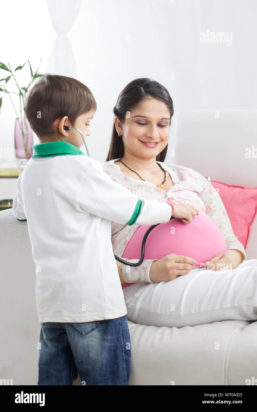 Boy examining his pregnant mother with stethoscope Stock Photo