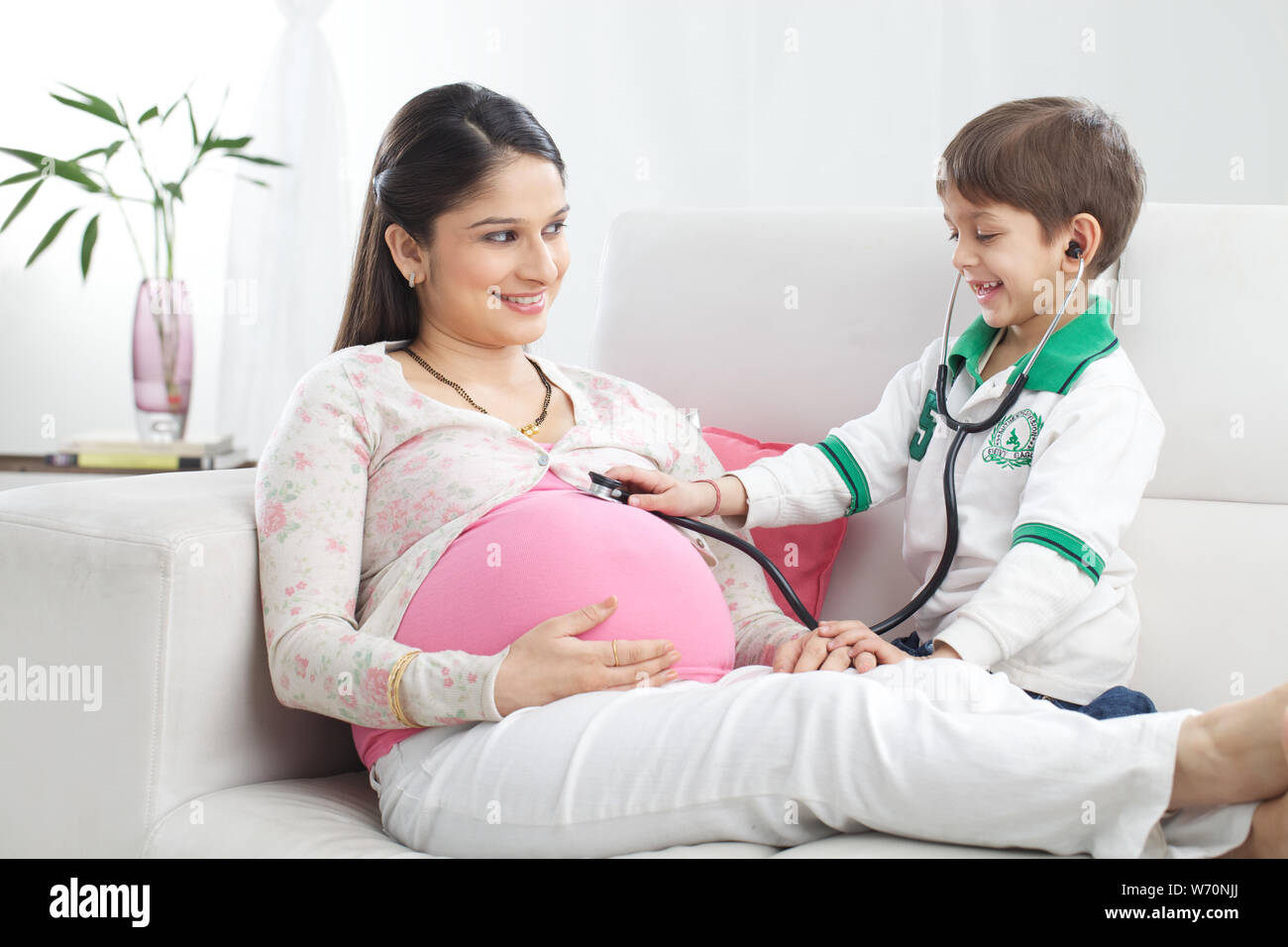 Boy examining his pregnant mother with stethoscope Stock Photo