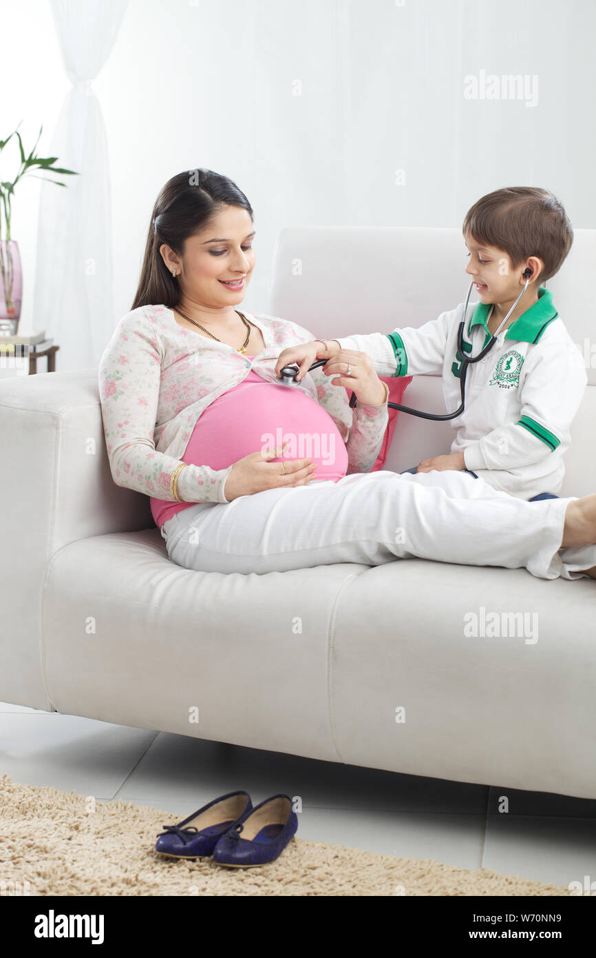 Boy examining his pregnant mother with stethoscope Stock Photo