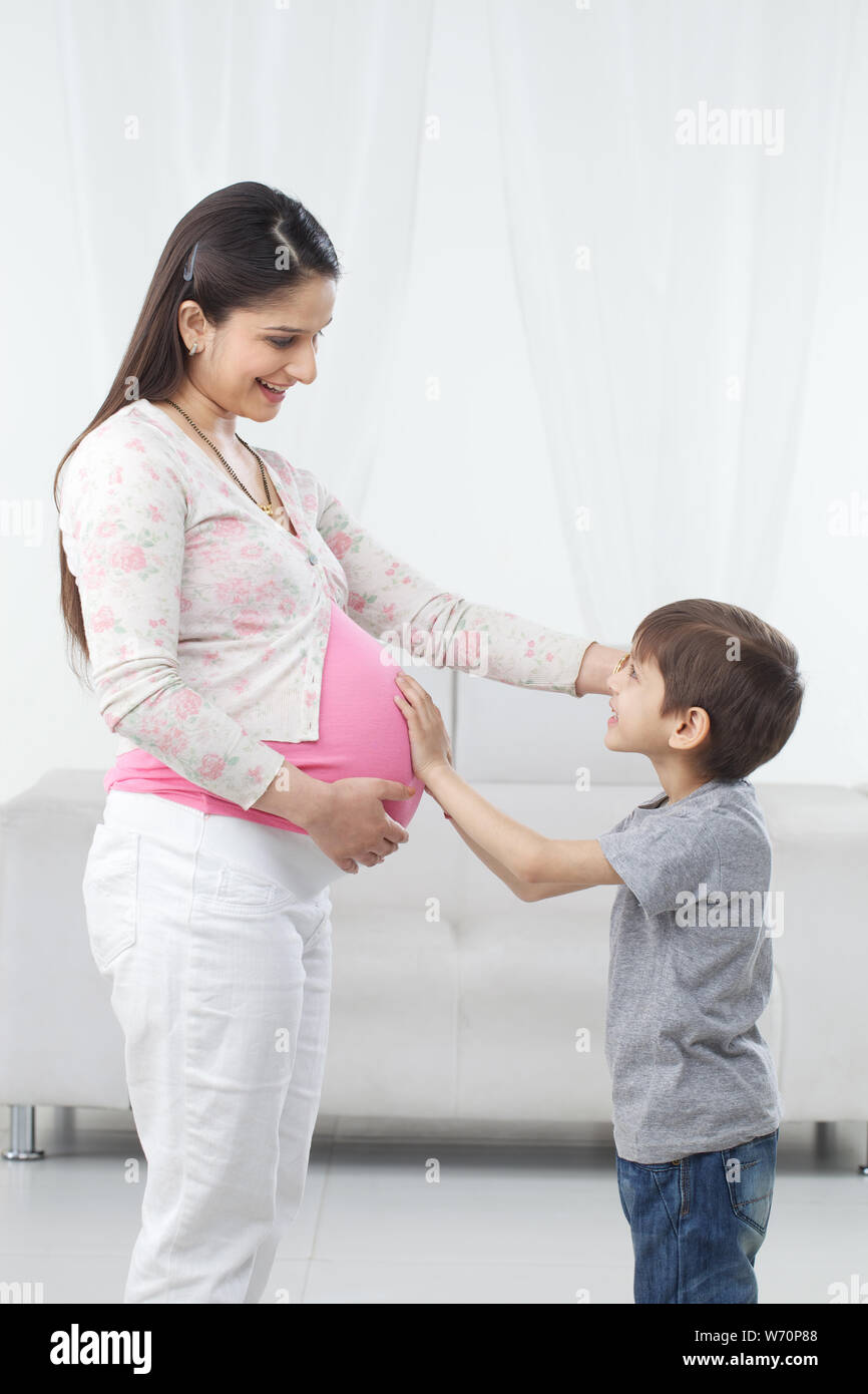 Boy touching stomach of his pregnant mother feeling movement of his