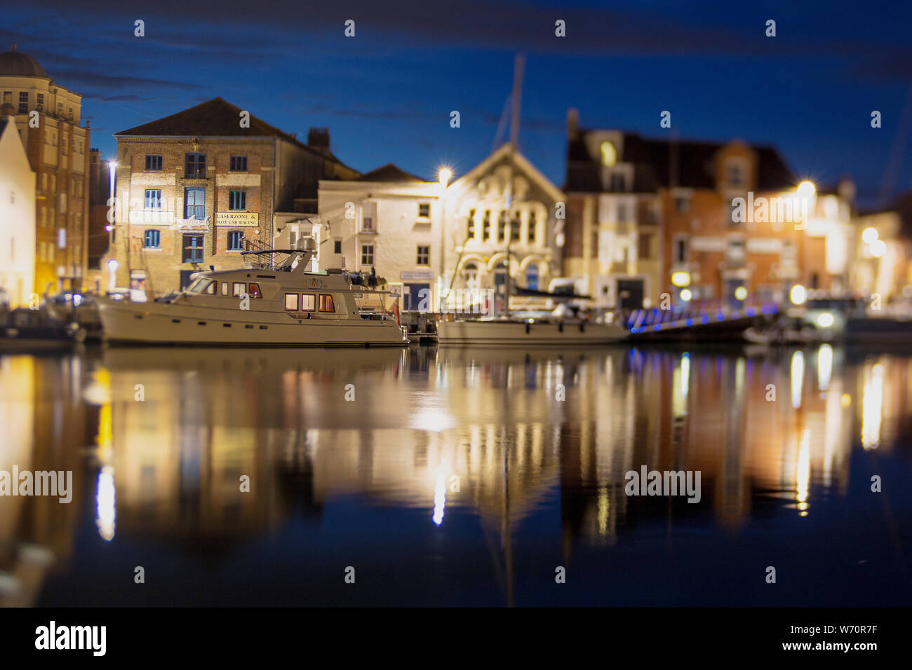 A night time shot of boats moored alongside Custom House Quay in Weymouth's Outer Harbour taken with a lensbaby lens Stock Photo