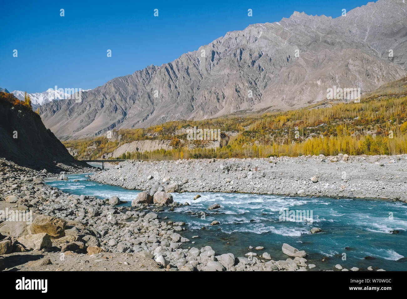 Turquoise blue river flowing through Hunza Nagar valley in autumn season with a view of Karakoram mountain range. Gilgit Baltistan, Pakistan. Stock Photo