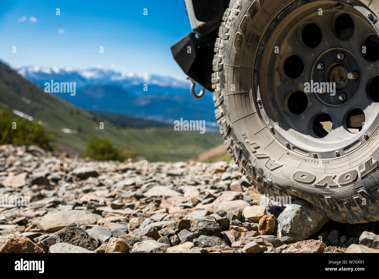 Jeep on dirt road in Sierras with mountain peaks and green valley Stock