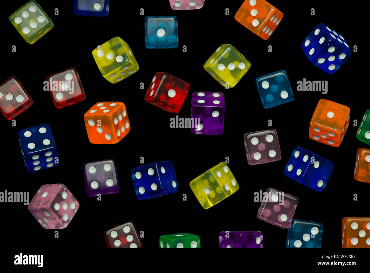 many falling translucent  multicolored  dices with white dots on black background Stock Photo