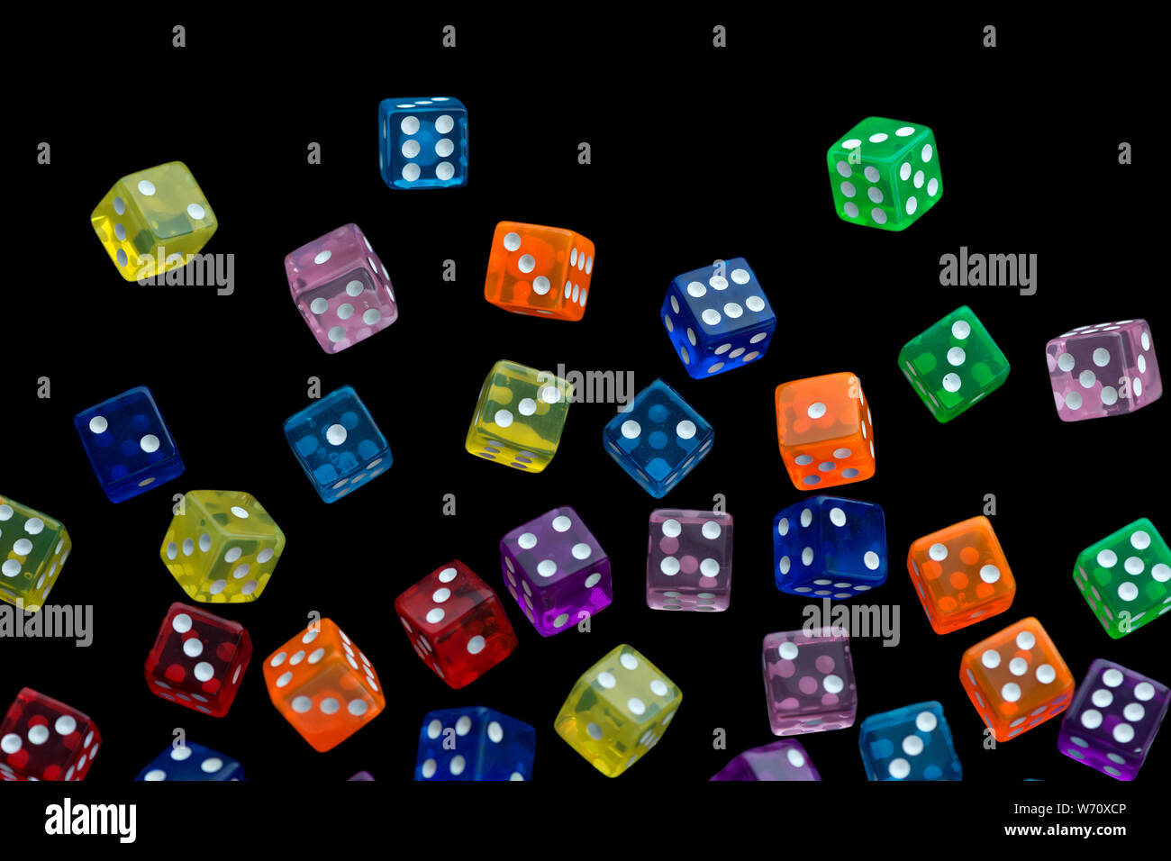 many falling translucent  multicolored  dices with white dots on black background Stock Photo