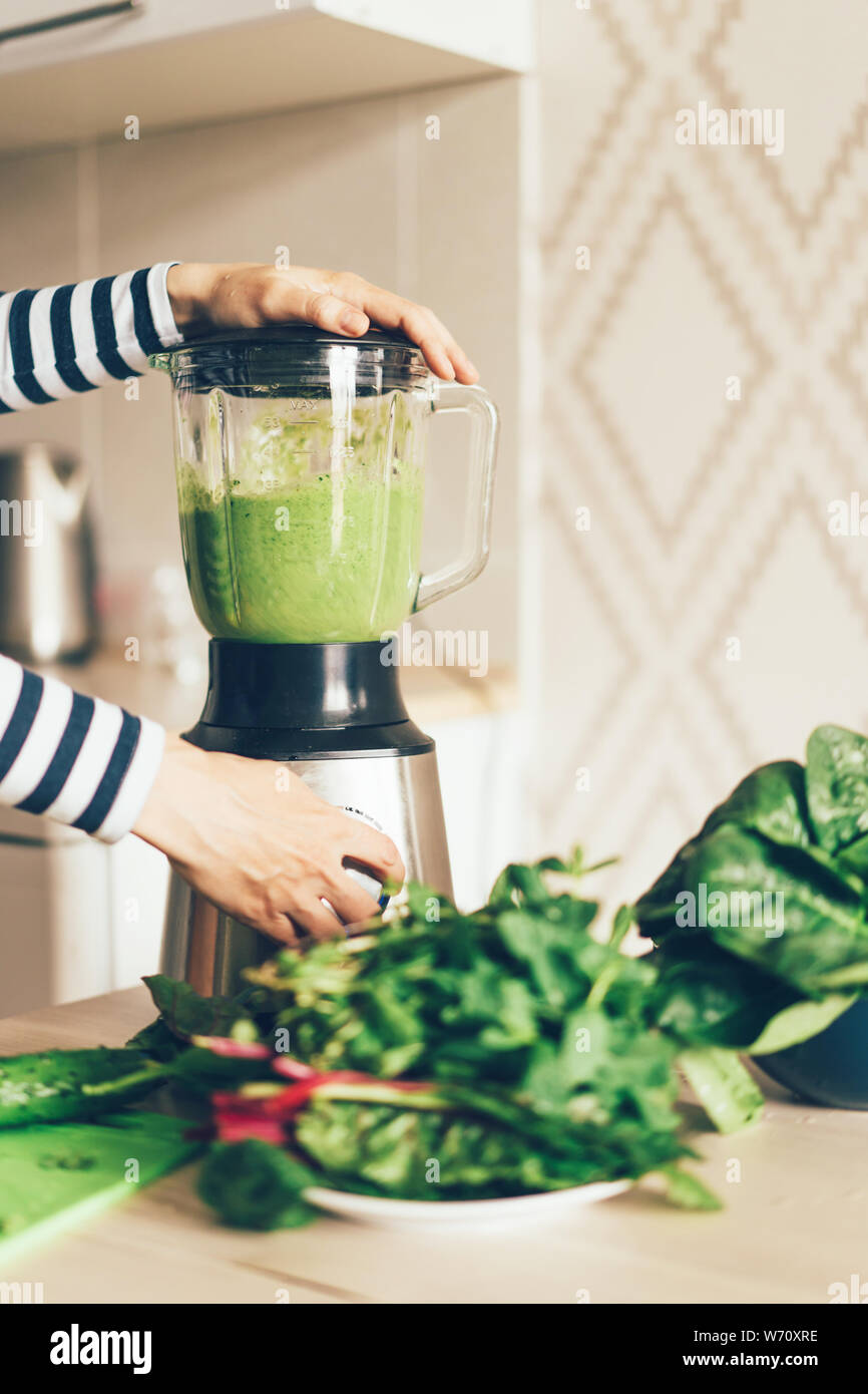 closeup woman hands making green smoothie in blender bowl Stock Photo