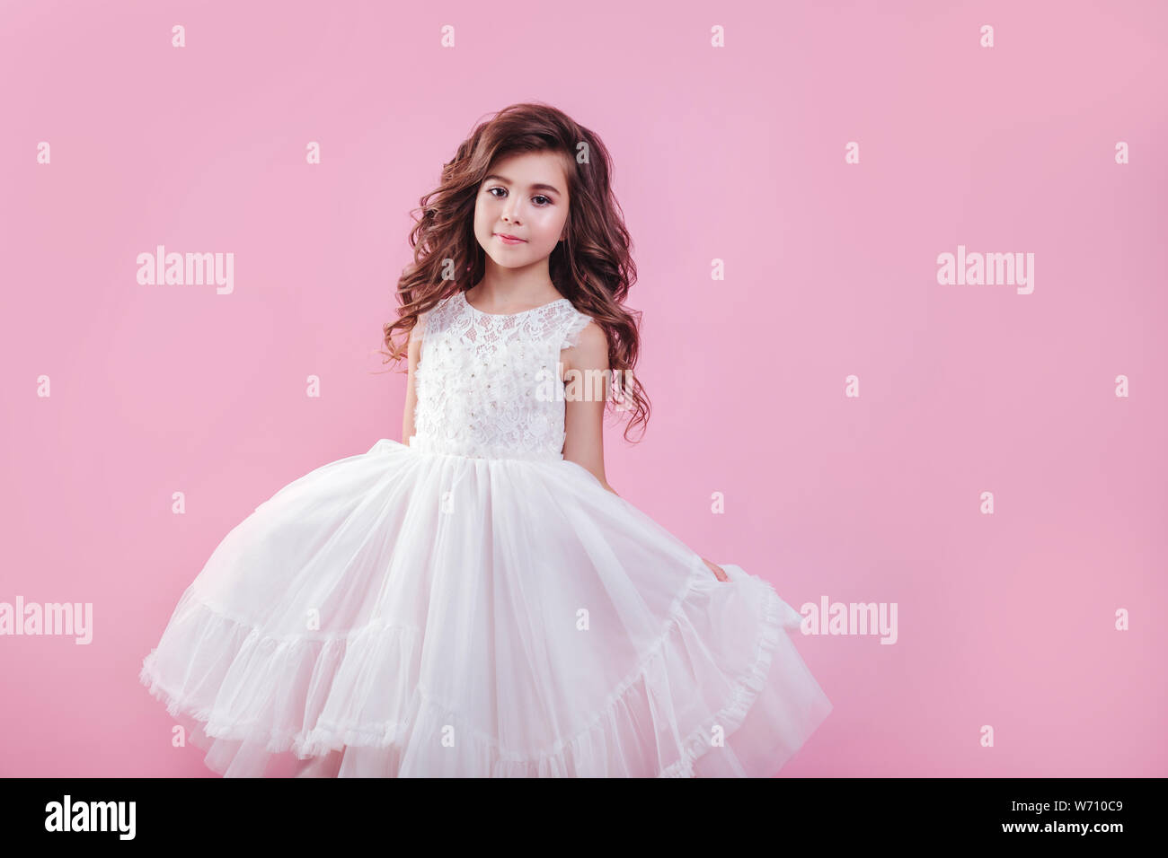 portrait of beautiful little girl in white dress on pink background ...