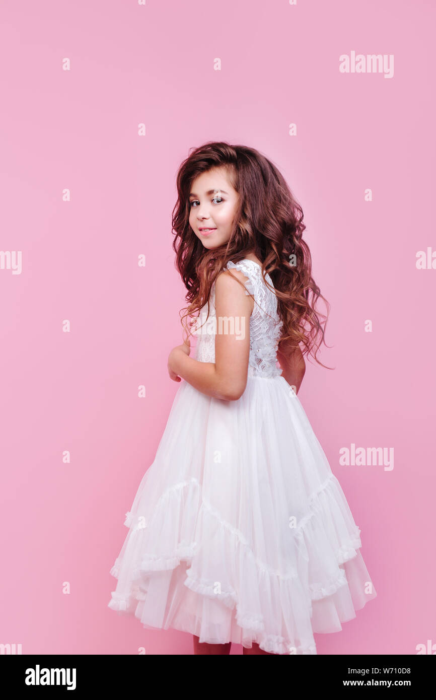 portrait of beautiful little girl in white dress on pink background ...