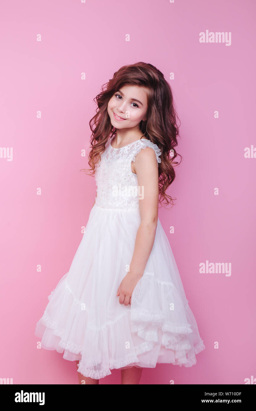 portrait of beautiful little girl in white dress on pink background ...