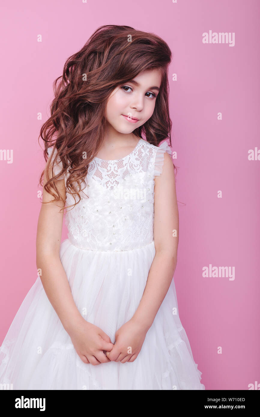 portrait of beautiful little girl in white dress on pink background ...