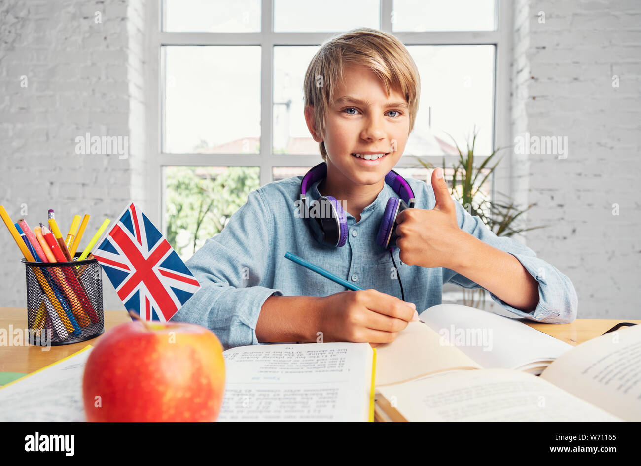 Portrait of successful teenage schoolboy sitting in the classrooom Stock Photo