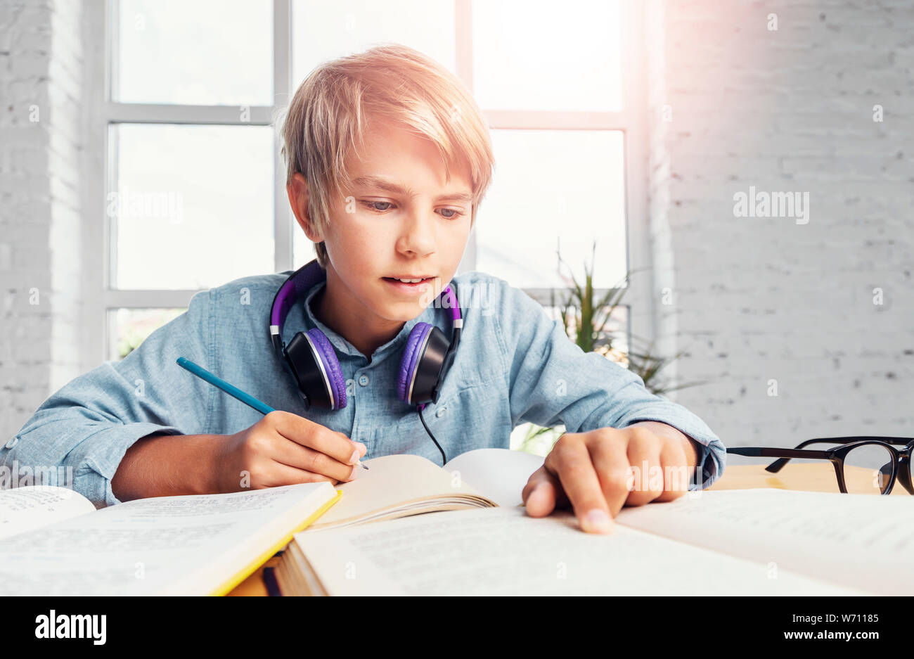 Happy young blonde schoolboy studying in wide classroom Stock Photo