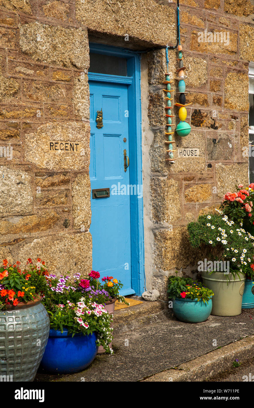 UK, England, Cornwall, Mousehole, North Street, floral planters outside door of Regent House, traditional granite built property Stock Photo