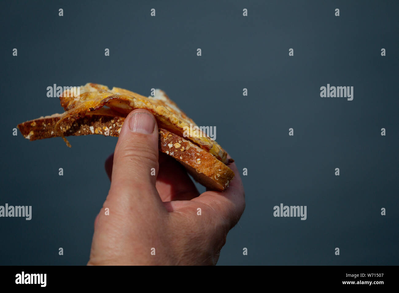 Hand holding an egg sandwich against the sky Stock Photo