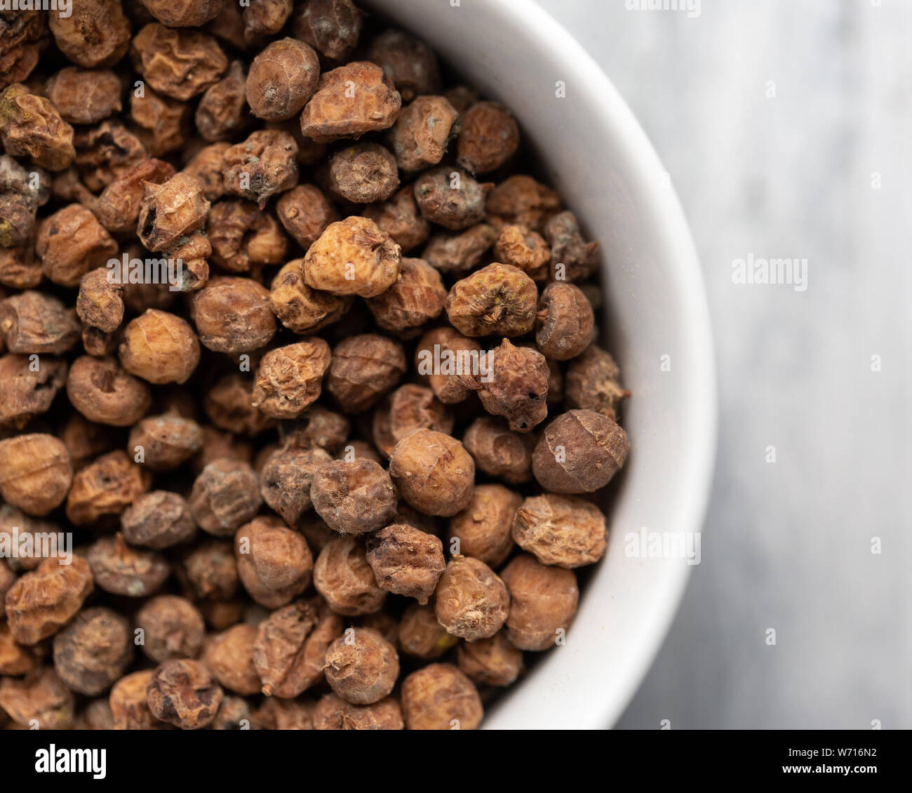 Tiger nuts in a white bowl, off centre to the left Stock Photo